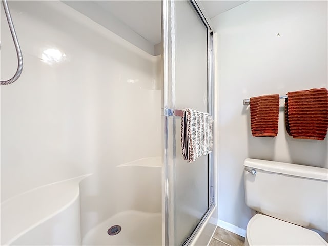 bathroom with tile patterned floors, a shower with door, and toilet