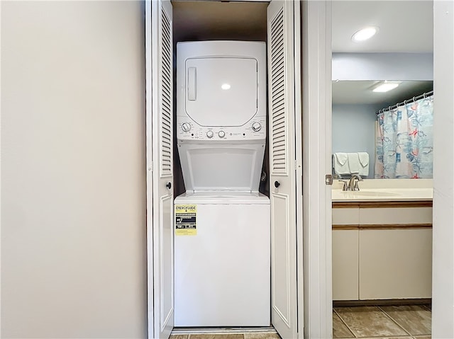 laundry area with stacked washer / drying machine, light tile patterned floors, and sink