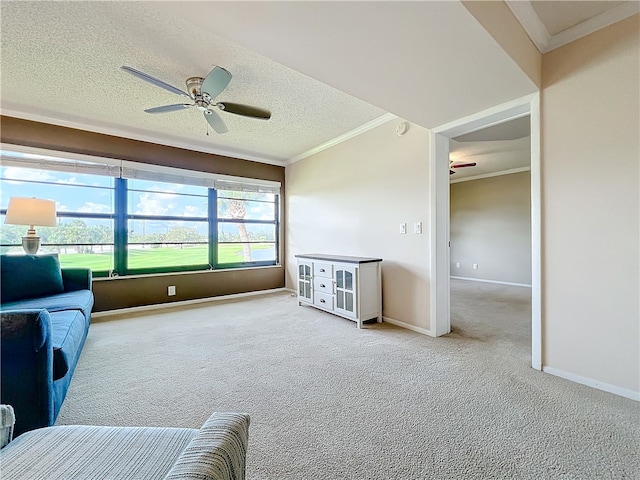 sitting room with ceiling fan, light colored carpet, ornamental molding, and a textured ceiling