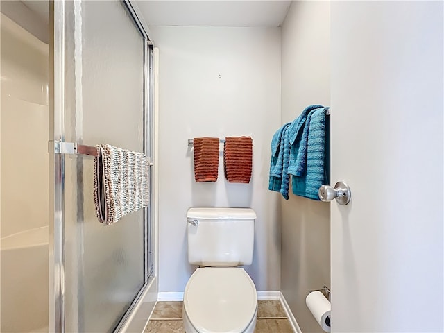 bathroom featuring toilet, tile patterned floors, and a shower with shower door