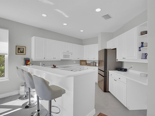 5235 W Harbor Village Dr, Vero Beach, FL 32967 - kitchen with white microwave, visible vents, a breakfast bar, white cabinets, and open shelves