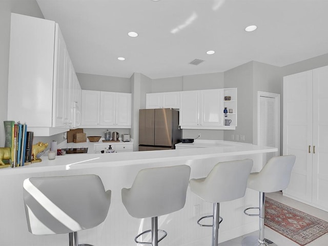 5235 W Harbor Village Dr, Vero Beach, FL 32967 - kitchen featuring visible vents, white cabinets, light countertops, and freestanding refrigerator