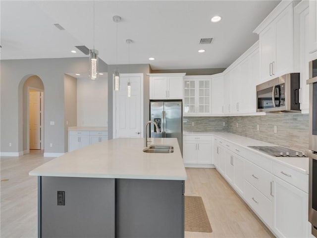 kitchen featuring white cabinets, an island with sink, stainless steel appliances, and decorative light fixtures