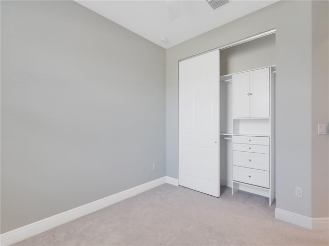 unfurnished bedroom with ceiling fan, a closet, and light colored carpet