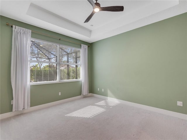 spare room with carpet, ceiling fan, and a tray ceiling