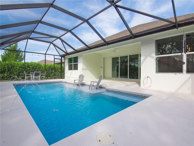 view of pool featuring glass enclosure, pool water feature, a patio area, and ceiling fan