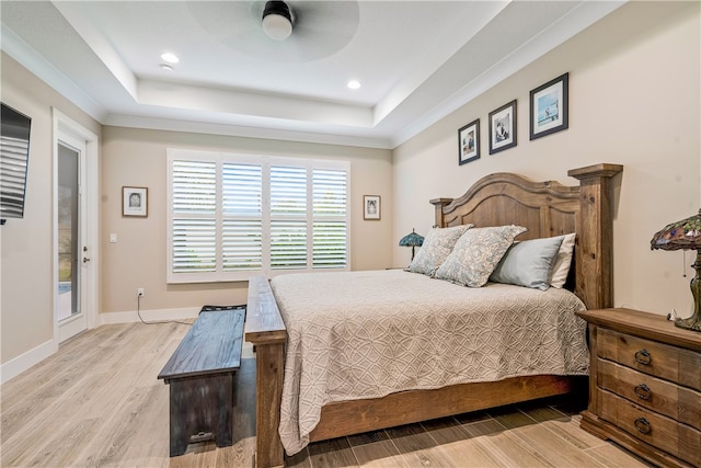 bedroom featuring a raised ceiling, ceiling fan, and light wood-type flooring