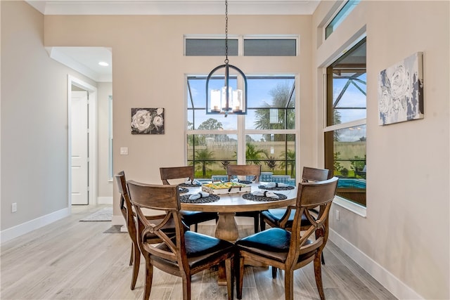 dining space featuring ornamental molding, light hardwood / wood-style flooring, and a notable chandelier