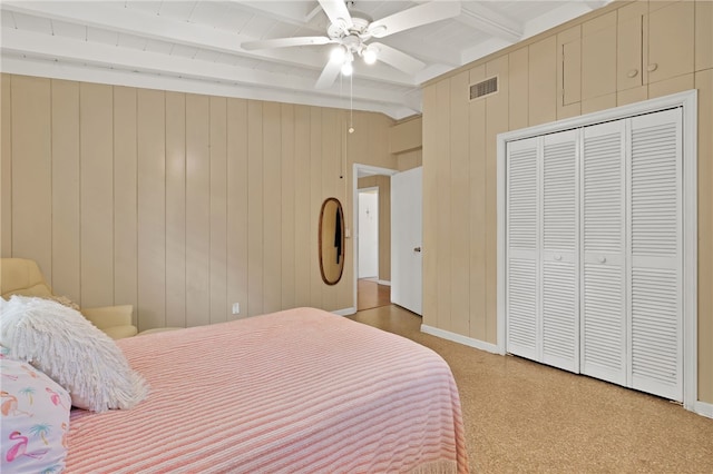 bedroom featuring ceiling fan, lofted ceiling with beams, a closet, and wood walls