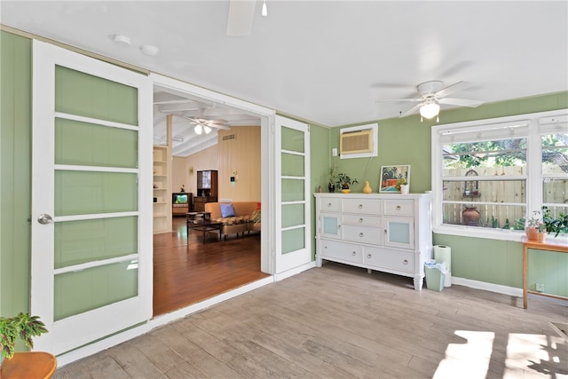 sunroom featuring lofted ceiling, a wall mounted AC, ceiling fan, and french doors