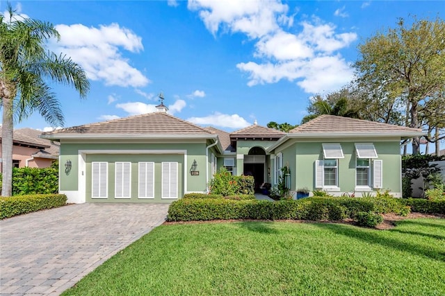 mediterranean / spanish-style house with an attached garage, stucco siding, decorative driveway, and a front yard