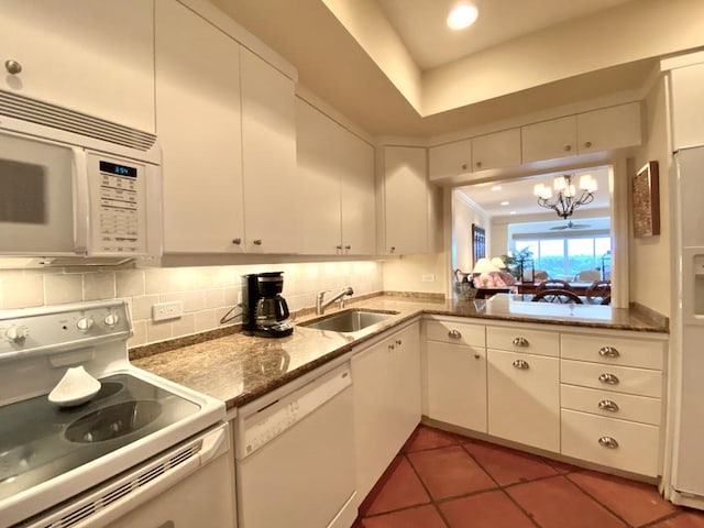 kitchen with sink, dark tile patterned floors, a notable chandelier, white appliances, and white cabinets