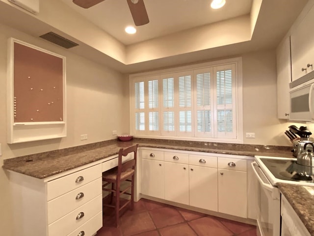 kitchen featuring white cabinetry, a raised ceiling, dark tile patterned floors, white appliances, and built in desk