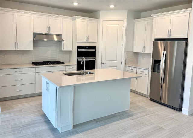 kitchen featuring stainless steel fridge with ice dispenser, under cabinet range hood, double wall oven, black gas cooktop, and a sink