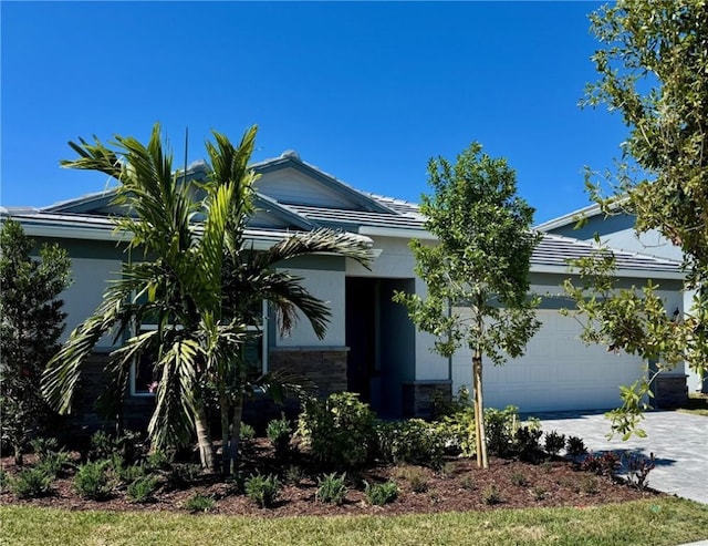 view of front of property with stone siding, stucco siding, an attached garage, and decorative driveway