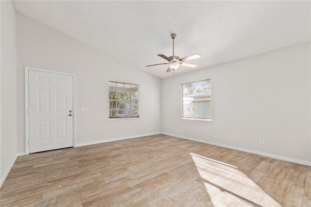 empty room featuring ceiling fan, light hardwood / wood-style floors, a textured ceiling, and vaulted ceiling