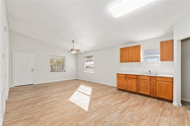 kitchen with ceiling fan, lofted ceiling, sink, and light hardwood / wood-style flooring