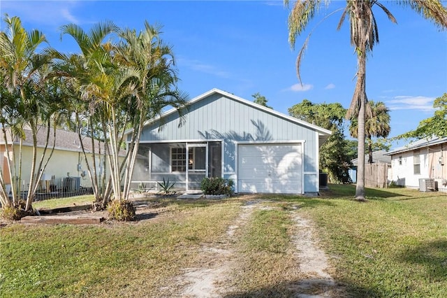 view of front of property with a front lawn, cooling unit, and a garage