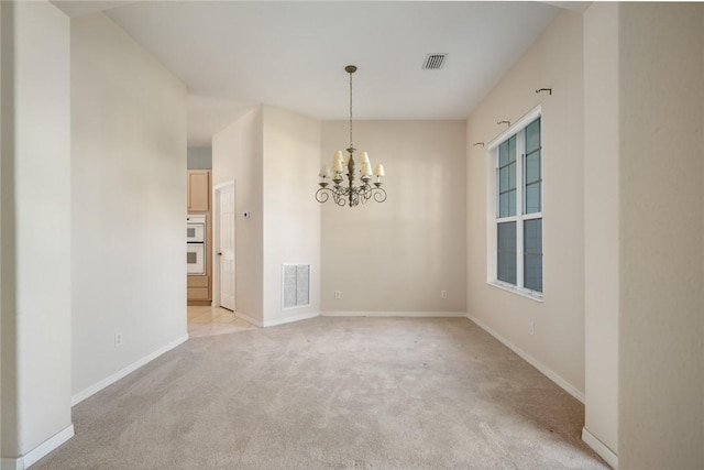 carpeted empty room featuring an inviting chandelier