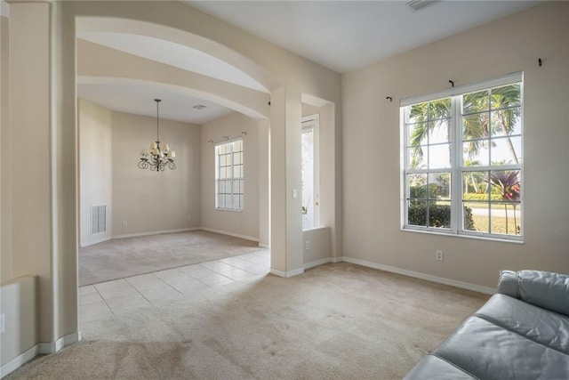 unfurnished living room featuring a wealth of natural light, light colored carpet, and a chandelier