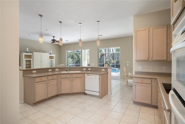 kitchen with light brown cabinetry, dishwasher, sink, and hanging light fixtures