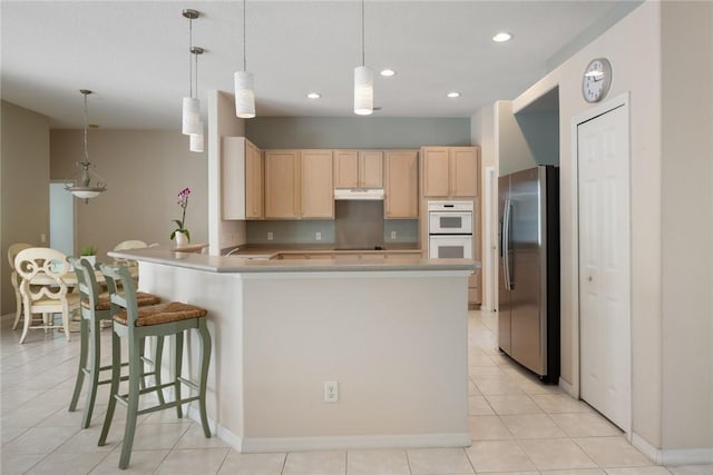 kitchen featuring stainless steel refrigerator with ice dispenser, a breakfast bar, light brown cabinetry, decorative light fixtures, and kitchen peninsula