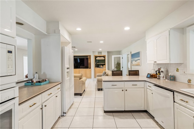 kitchen featuring white cabinetry, kitchen peninsula, tasteful backsplash, light tile patterned floors, and white appliances