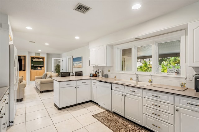 kitchen with sink, kitchen peninsula, white appliances, white cabinets, and decorative backsplash