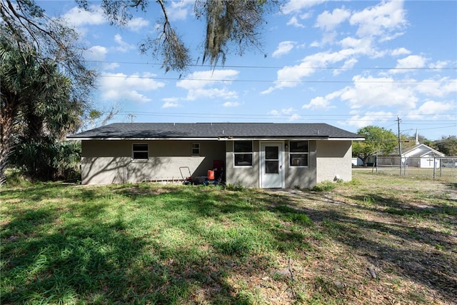 rear view of property with fence, a lawn, and stucco siding