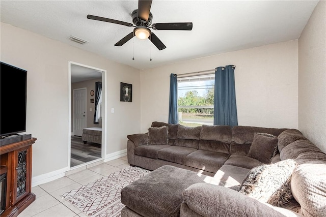 living area featuring visible vents, light tile patterned flooring, a ceiling fan, and baseboards