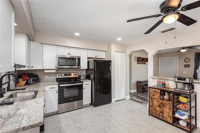 kitchen with stainless steel appliances, a sink, visible vents, white cabinetry, and light stone countertops