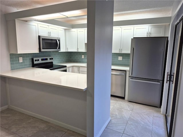 kitchen featuring backsplash, light tile patterned floors, appliances with stainless steel finishes, white cabinetry, and kitchen peninsula