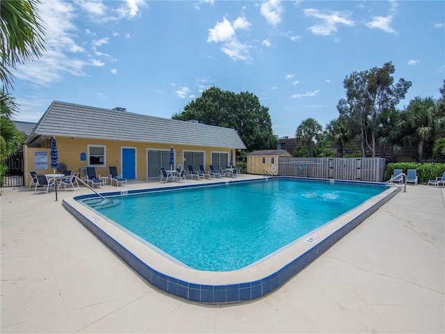 view of swimming pool with a storage unit and a patio area