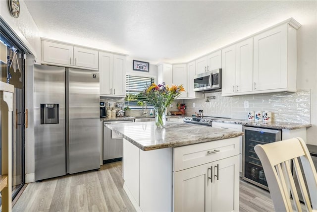 1458 N Lawnwood Cir Unit 29C, Fort Pierce, FL 34950 - kitchen with stainless steel appliances, wine cooler, light wood-type flooring, decorative backsplash, and light stone counters