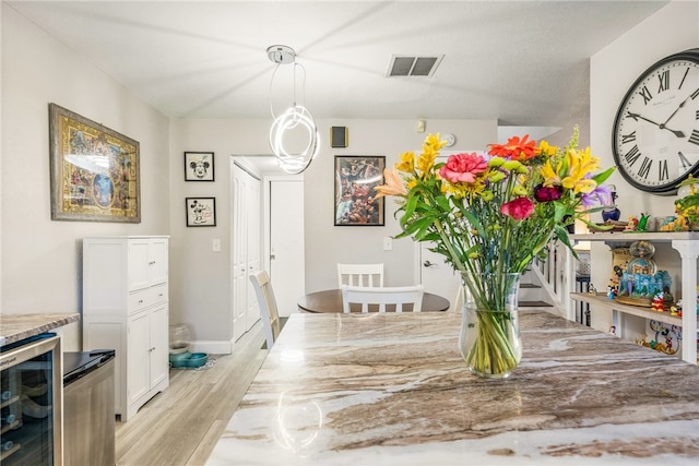 dining space featuring beverage cooler and light hardwood / wood-style flooring