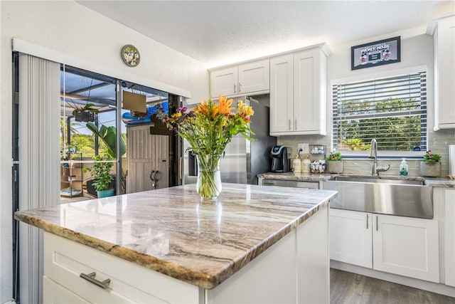 kitchen with tasteful backsplash, light wood-type flooring, sink, and white cabinetry