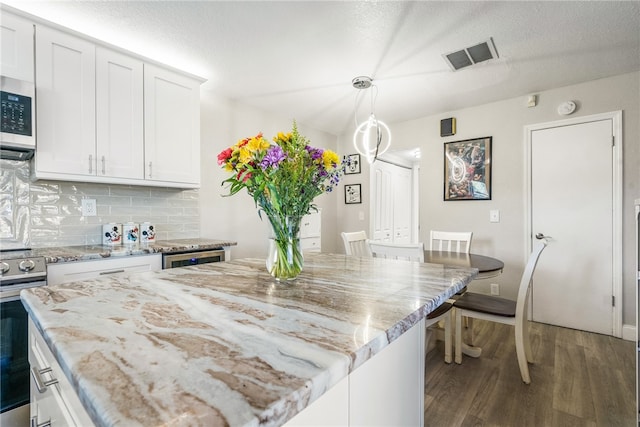 kitchen with a center island, dark hardwood / wood-style floors, white cabinetry, appliances with stainless steel finishes, and decorative light fixtures