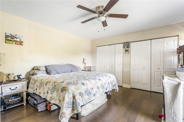 bedroom featuring ceiling fan, dark hardwood / wood-style floors, and two closets