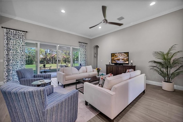 living area featuring arched walkways, ornamental molding, wood finished floors, and baseboards