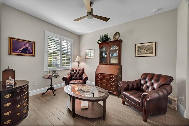 sitting room with ceiling fan, wood finished floors, visible vents, and baseboards