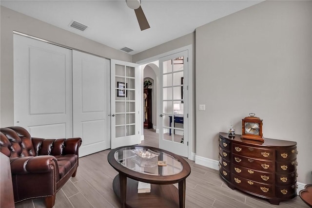 sitting room featuring arched walkways, ceiling fan, visible vents, baseboards, and wood tiled floor