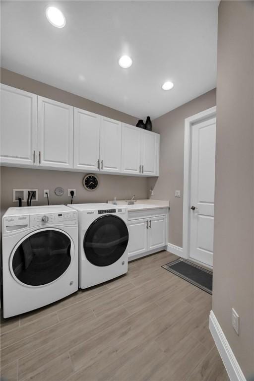 washroom featuring light wood-style flooring, recessed lighting, separate washer and dryer, baseboards, and cabinet space