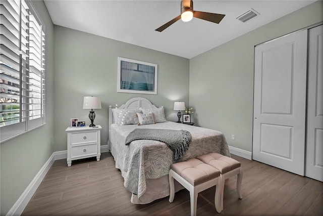 bedroom with a ceiling fan, wood finished floors, visible vents, and baseboards