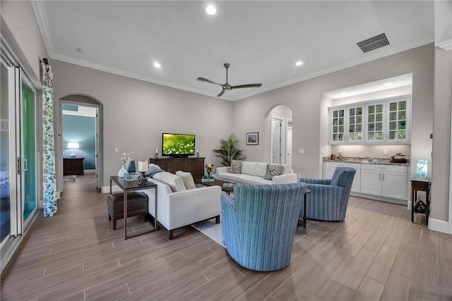 living area with arched walkways, visible vents, wood tiled floor, ceiling fan, and baseboards