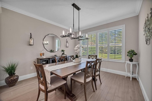 dining space featuring a notable chandelier, crown molding, light wood-style flooring, and baseboards