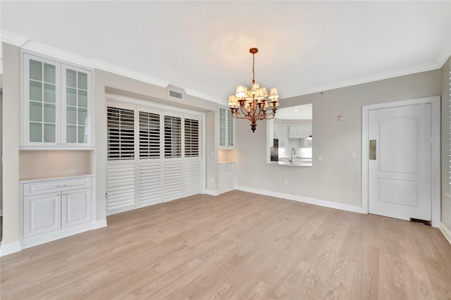 unfurnished dining area with light hardwood / wood-style flooring, sink, crown molding, and an inviting chandelier