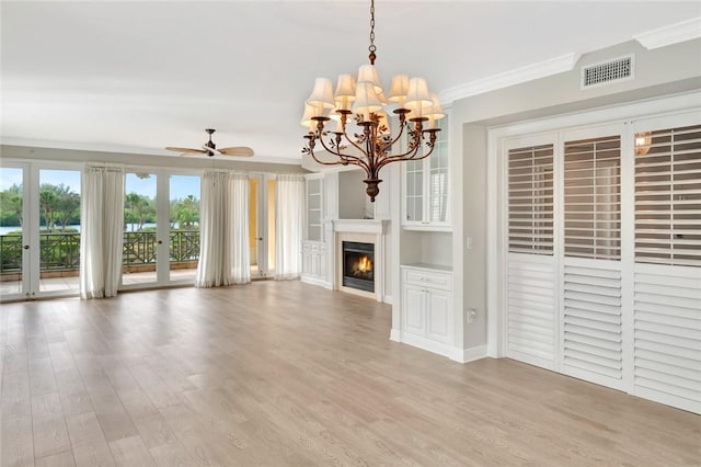 unfurnished living room featuring crown molding, built in features, ceiling fan with notable chandelier, and light hardwood / wood-style flooring