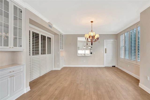 unfurnished dining area featuring a notable chandelier, light wood-type flooring, and crown molding