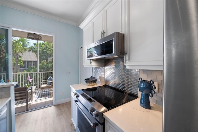 1235 Winding Oaks Cir E Unit 505, Vero Beach, FL 32963 - kitchen with stainless steel appliances, ornamental molding, white cabinets, light wood-style flooring, and backsplash