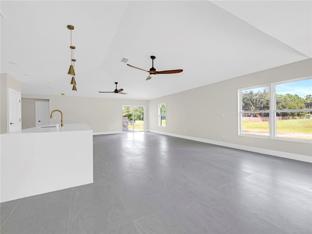 unfurnished living room with a wealth of natural light, sink, and ceiling fan